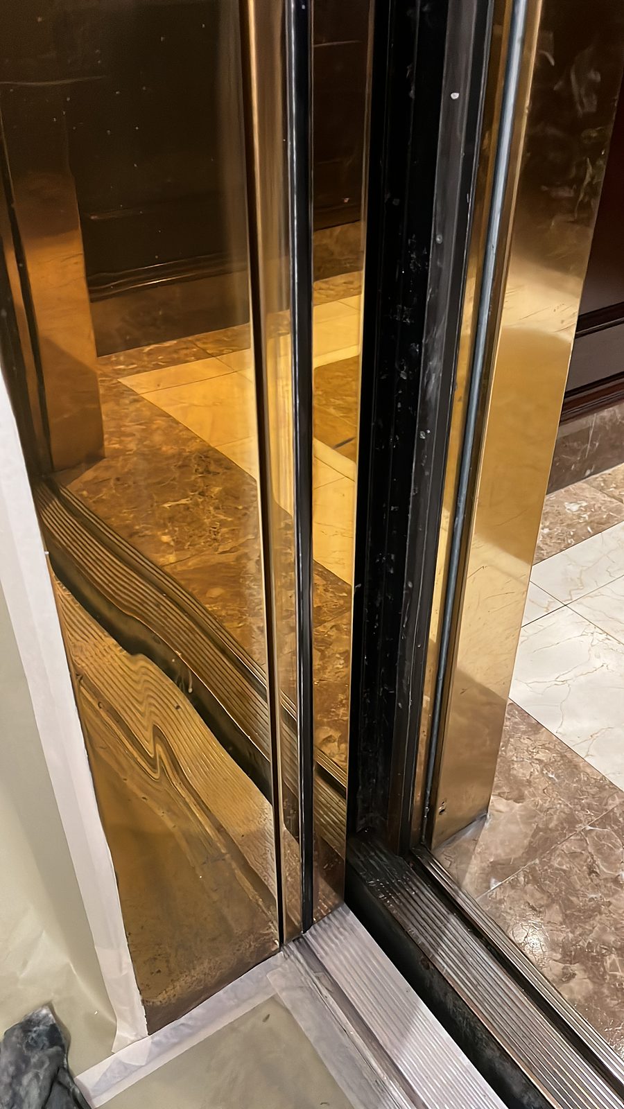 Mirror-polished brass panels reflecting the lobby floor